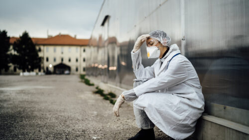 Depressed crying doctor with mask having mental breakdown.