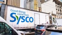 A Sysco truck with a branded message makes it way through traffic.